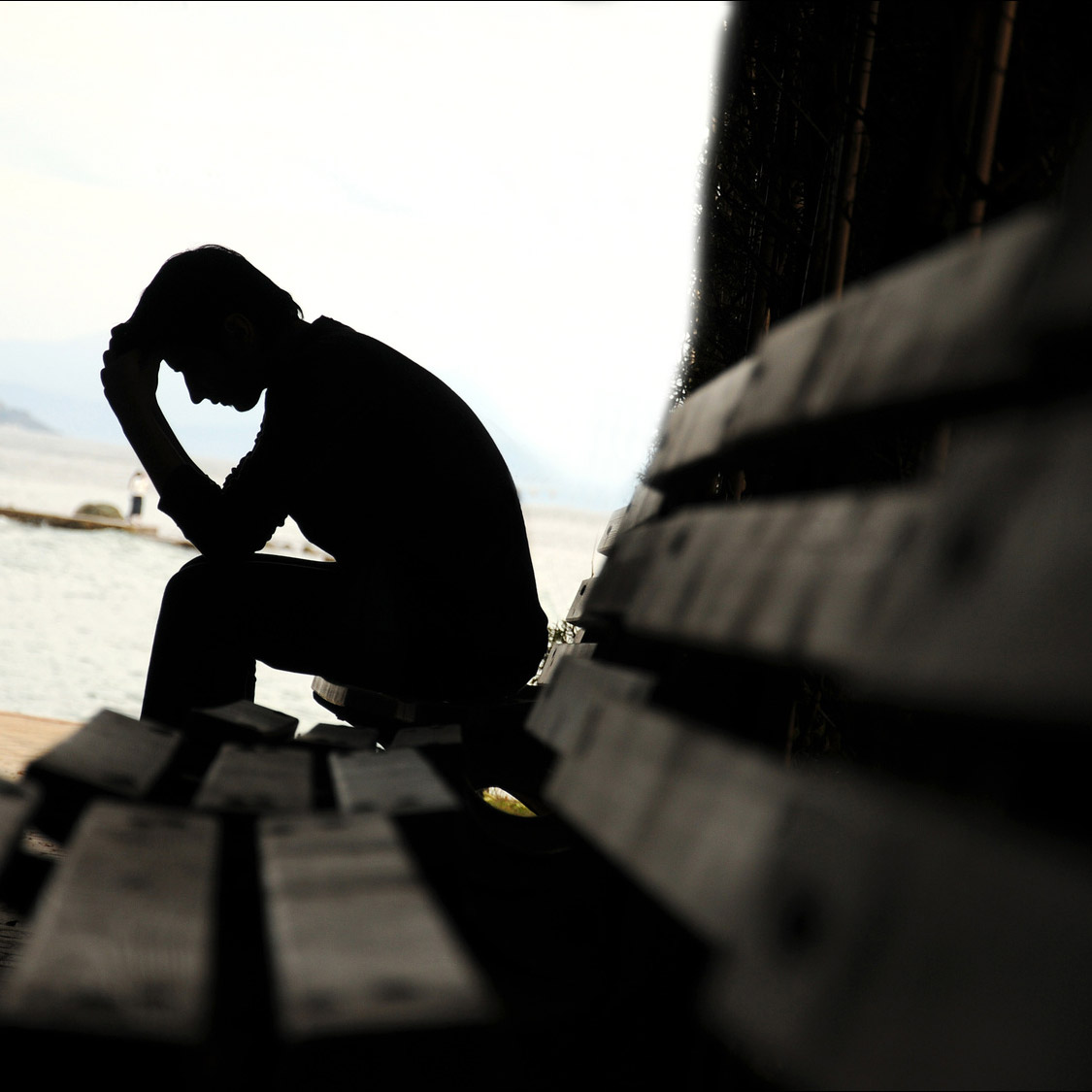 A man sitting on a bench with his head in his hands